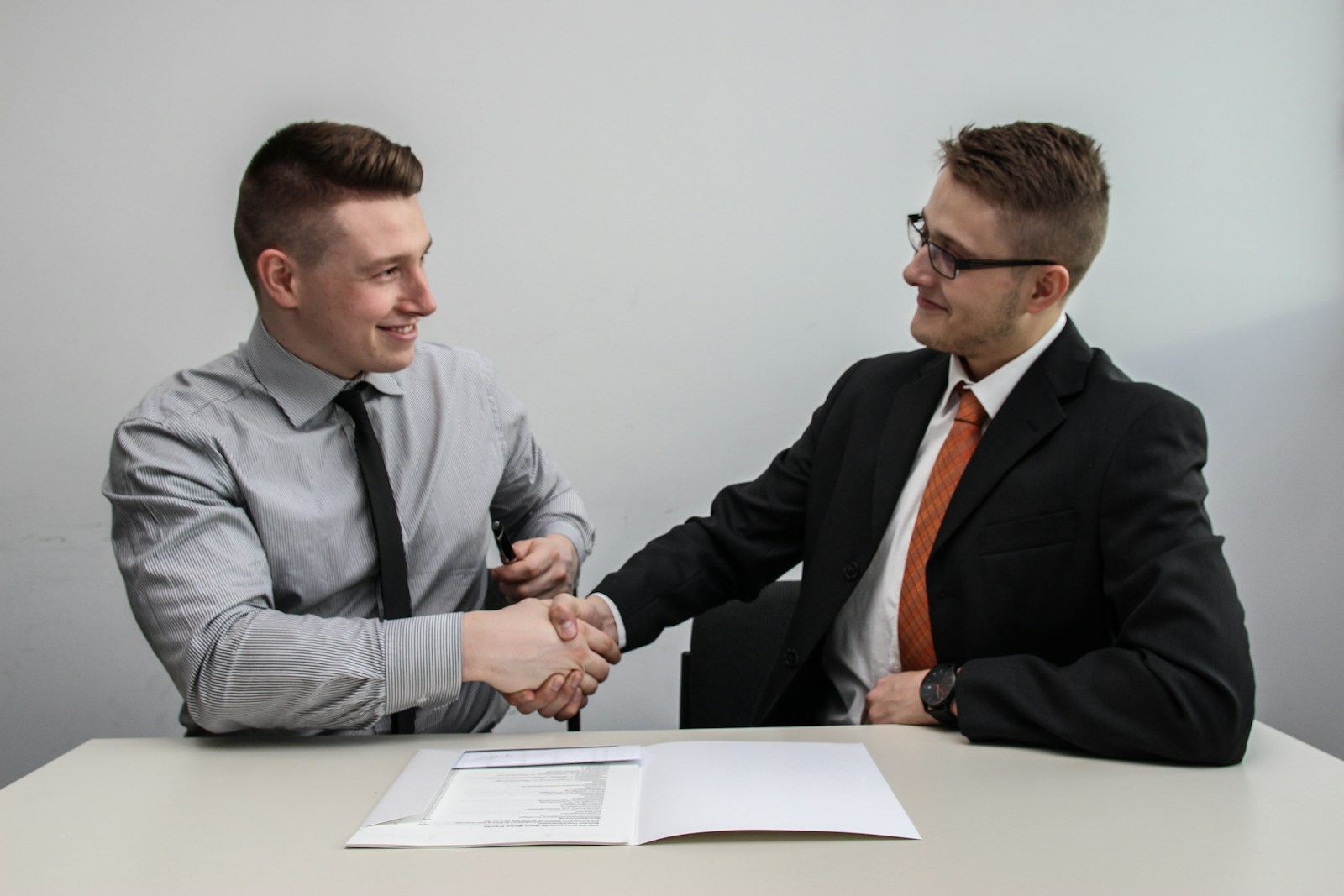 Photo by Sebastian Herrmann two men facing each other while shake hands and smiling